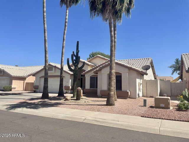 8759 W Port Au Prince Ln, Peoria, AZ 85381 - view of front of property featuring a tile roof, driveway, an attached garage, and stucco siding