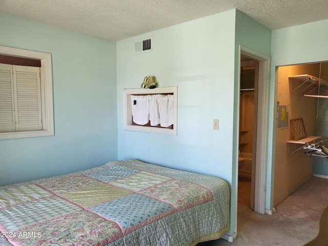 bedroom featuring a walk in closet, a closet, carpet floors, and a textured ceiling