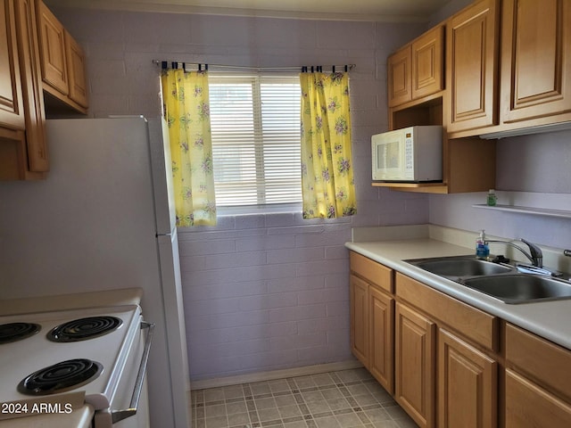 kitchen with white appliances, light tile patterned floors, brick wall, and sink