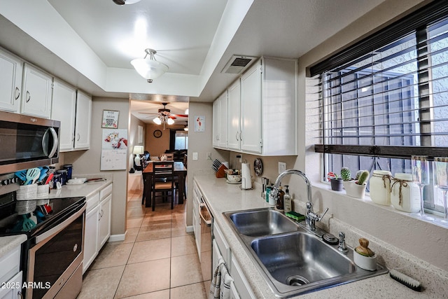 kitchen with light tile patterned floors, stainless steel appliances, white cabinetry, and sink