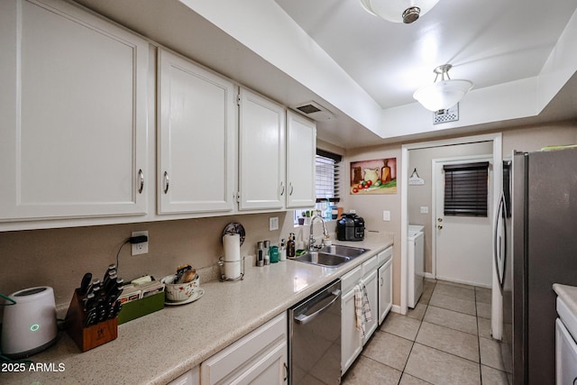 kitchen with stainless steel appliances, sink, light tile patterned floors, white cabinets, and washer / clothes dryer