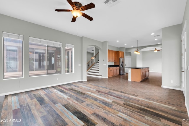 18544 E Caledonia Dr, Queen Creek, AZ 85142 - unfurnished living room with arched walkways, visible vents, dark wood-type flooring, and a ceiling fan