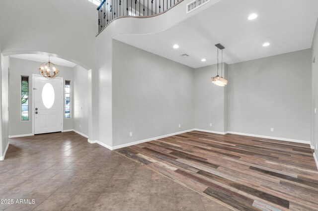 18544 E Caledonia Dr, Queen Creek, AZ 85142 - foyer entrance featuring wood finished floors, visible vents, baseboards, an inviting chandelier, and arched walkways