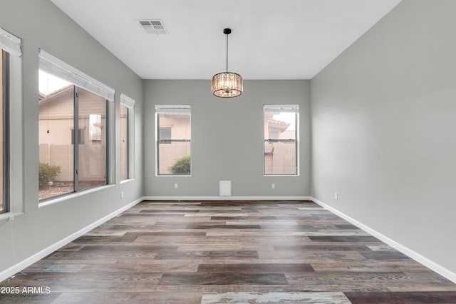 18544 E Caledonia Dr, Queen Creek, AZ 85142 - empty room with a notable chandelier, wood finished floors, visible vents, and baseboards