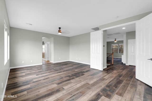 18544 E Caledonia Dr, Queen Creek, AZ 85142 - empty room with visible vents, dark wood-style floors, arched walkways, baseboards, and ceiling fan
