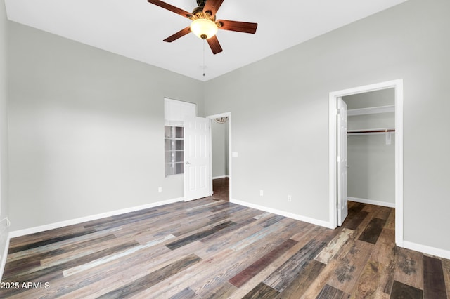18544 E Caledonia Dr, Queen Creek, AZ 85142 - unfurnished bedroom featuring a walk in closet, baseboards, and wood finished floors
