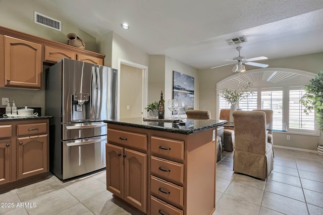 2984 N 152nd Dr, Goodyear, AZ 85395 - kitchen featuring stainless steel fridge with ice dispenser, a center island, ceiling fan, light tile patterned floors, and dark stone counters