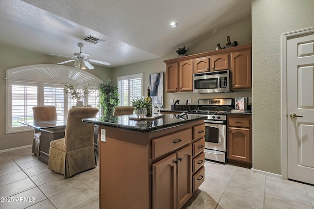 2984 N 152nd Dr, Goodyear, AZ 85395 - kitchen with appliances with stainless steel finishes, a kitchen island, healthy amount of natural light, light tile patterned floors, and lofted ceiling