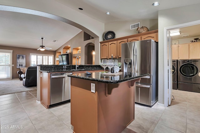 2984 N 152nd Dr, Goodyear, AZ 85395 - kitchen featuring stainless steel appliances, washing machine and clothes dryer, a center island, vaulted ceiling, and a ceiling fan