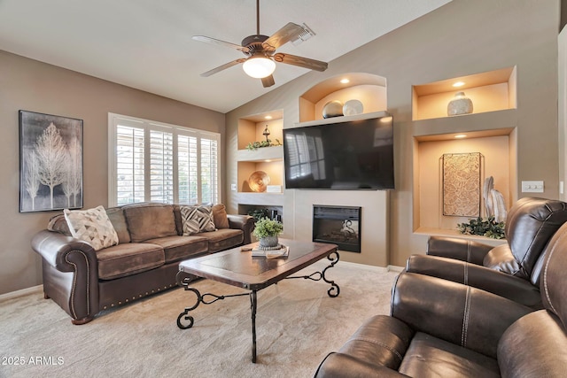 2984 N 152nd Dr, Goodyear, AZ 85395 - living room featuring ceiling fan, carpet flooring, a glass covered fireplace, lofted ceiling, and built in shelves