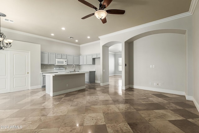 kitchen with white appliances, a kitchen island with sink, crown molding, sink, and ceiling fan with notable chandelier