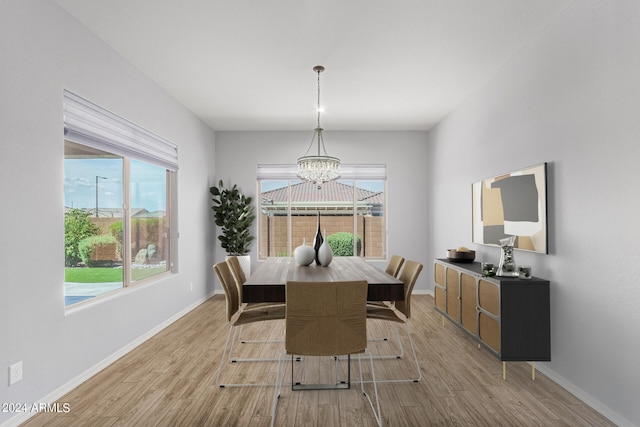 dining room featuring baseboards, light wood finished floors, a wealth of natural light, and an inviting chandelier