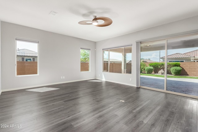 unfurnished room with dark wood-style floors, visible vents, baseboards, and ceiling fan