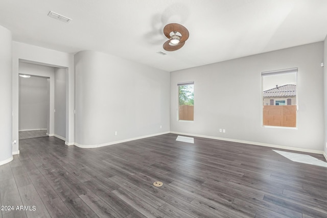 empty room featuring dark wood-type flooring, visible vents, and baseboards