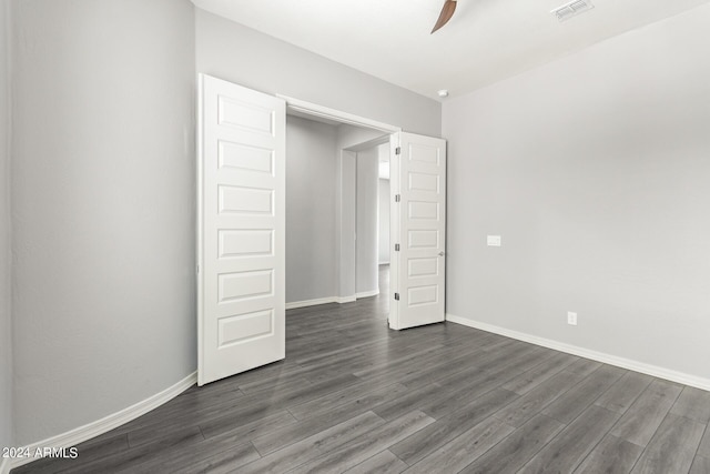 unfurnished bedroom featuring dark wood-type flooring, a ceiling fan, visible vents, and baseboards