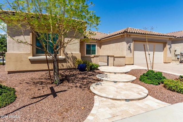 view of front facade with concrete driveway, a tiled roof, an attached garage, and stucco siding