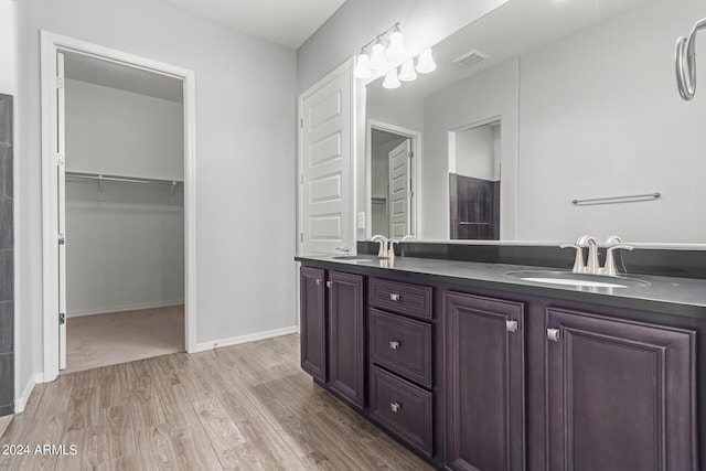 bathroom featuring double vanity, wood finished floors, a sink, and visible vents