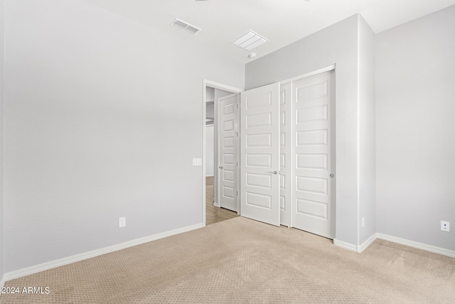 unfurnished bedroom with baseboards, a closet, visible vents, and light colored carpet