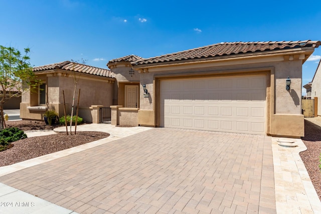 view of front of property with a garage, decorative driveway, a tile roof, and stucco siding