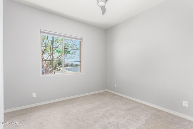 carpeted spare room featuring ceiling fan and baseboards