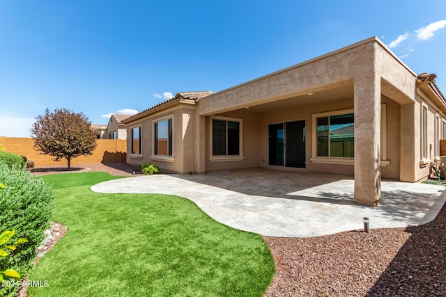 rear view of house featuring a lawn, a patio area, fence, and stucco siding