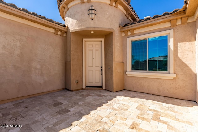 property entrance featuring a patio area, a tile roof, and stucco siding