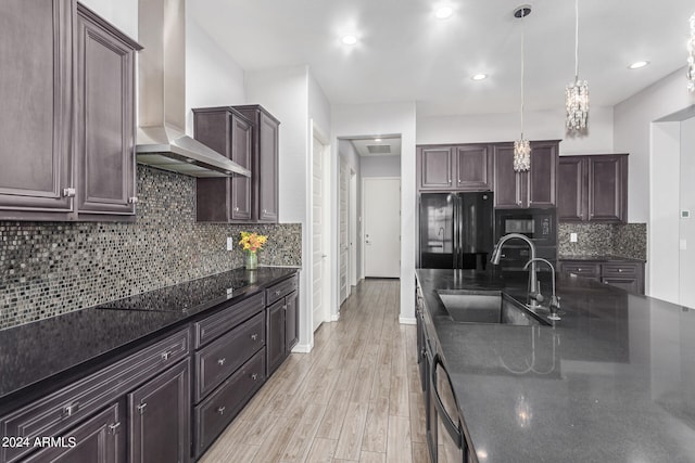 kitchen featuring light wood-type flooring, decorative backsplash, black appliances, sink, and wall chimney range hood