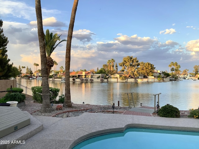 pool featuring a water view, fence, and a residential view