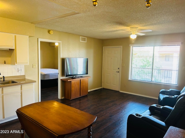 living room featuring a textured ceiling, ceiling fan, sink, and dark hardwood / wood-style floors