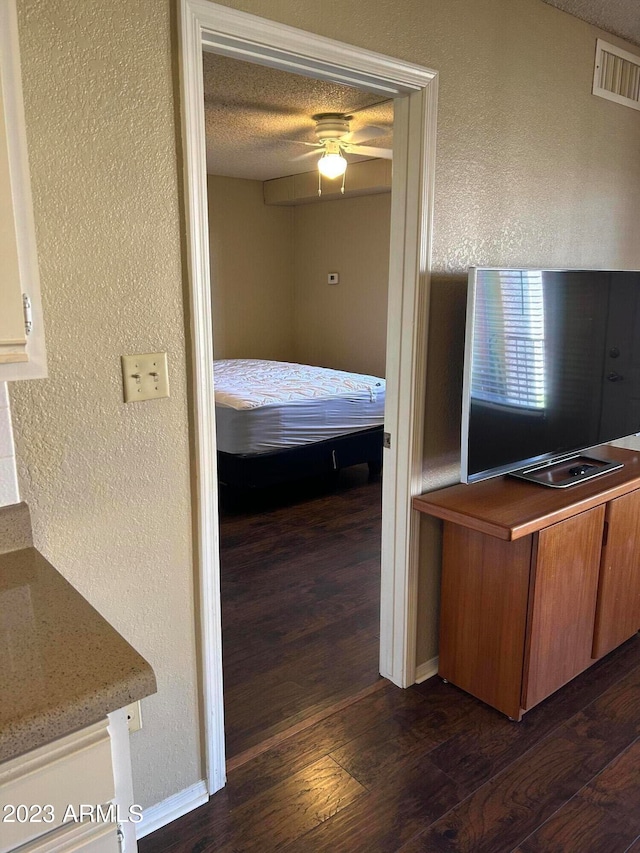 unfurnished bedroom with a textured ceiling, ceiling fan, and dark wood-type flooring