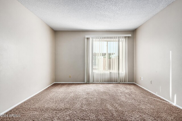 carpeted empty room featuring a textured ceiling