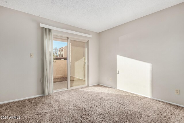 carpeted empty room featuring a textured ceiling