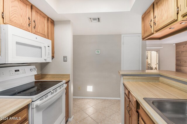 kitchen with sink, white appliances, and light tile patterned flooring