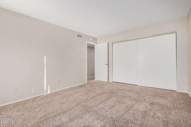 unfurnished bedroom with a closet, carpet floors, and a textured ceiling