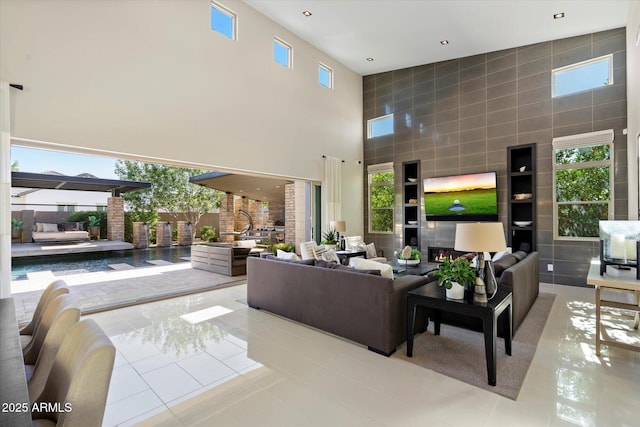 living area featuring a towering ceiling, tile patterned flooring, healthy amount of natural light, and tile walls