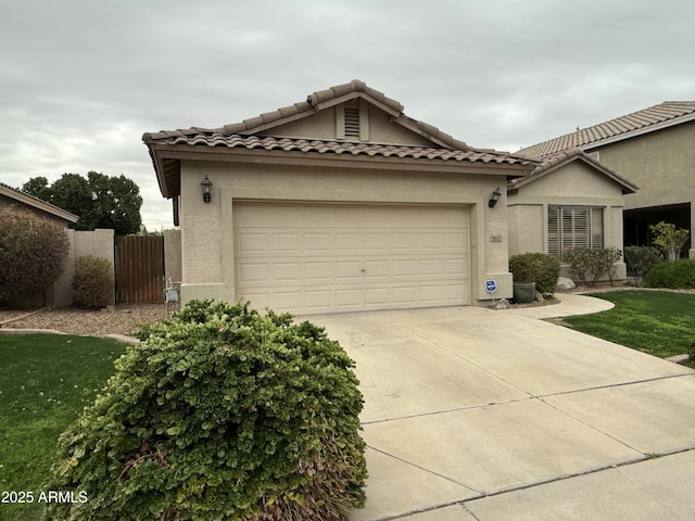 mediterranean / spanish-style home featuring stucco siding, fence, concrete driveway, a garage, and a tiled roof