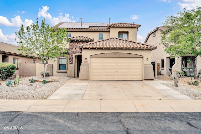 mediterranean / spanish-style house with stucco siding, a tile roof, concrete driveway, a garage, and solar panels