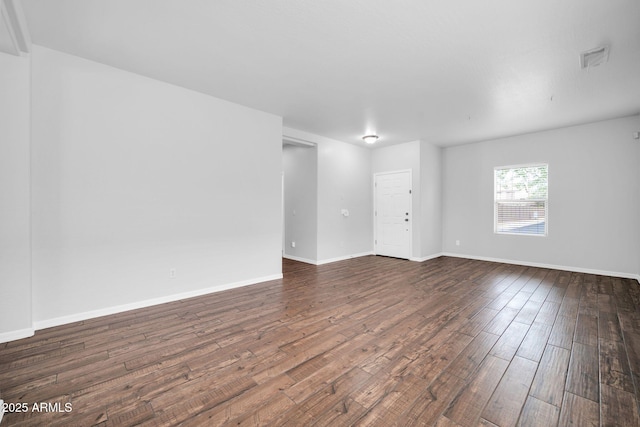 unfurnished room with visible vents, baseboards, and dark wood-style flooring