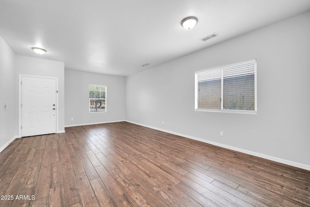 unfurnished room featuring dark wood finished floors, baseboards, and visible vents