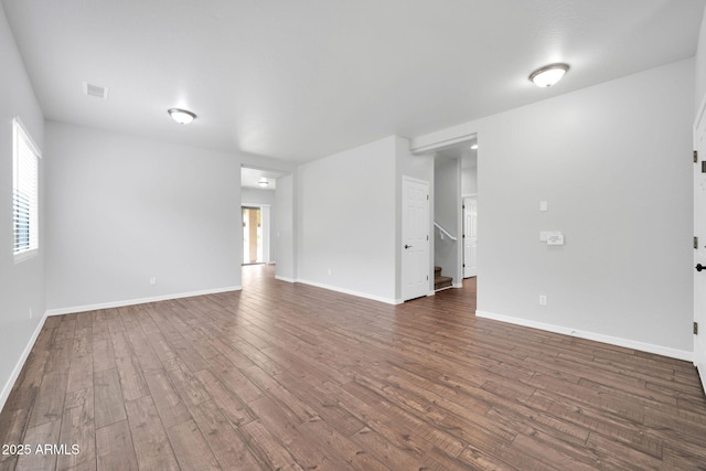 unfurnished living room featuring dark wood-style floors, visible vents, stairway, and baseboards