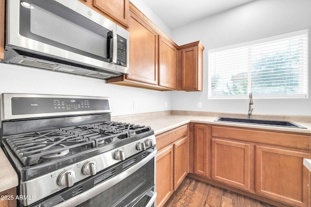 kitchen with a sink, light countertops, wood finished floors, and stainless steel appliances