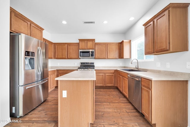 kitchen featuring visible vents, a kitchen island, appliances with stainless steel finishes, wood finished floors, and a sink