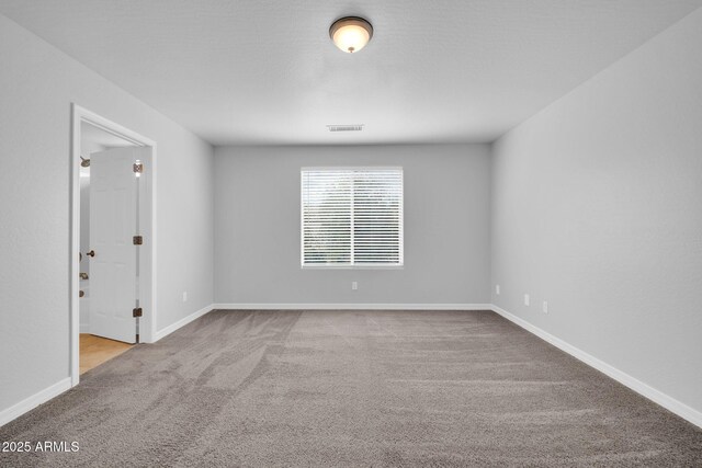 carpeted spare room with visible vents and baseboards