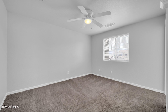 spare room featuring a ceiling fan, visible vents, dark colored carpet, and baseboards