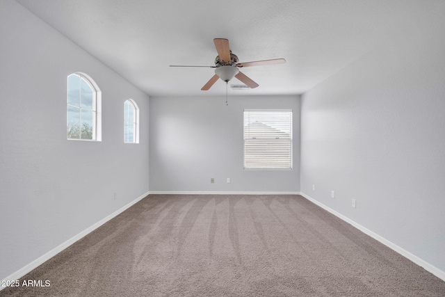 carpeted empty room featuring visible vents, baseboards, and ceiling fan