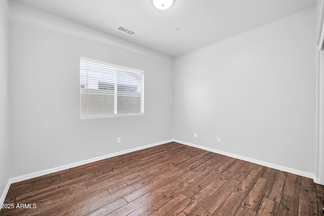 spare room featuring visible vents, dark wood-type flooring, and baseboards