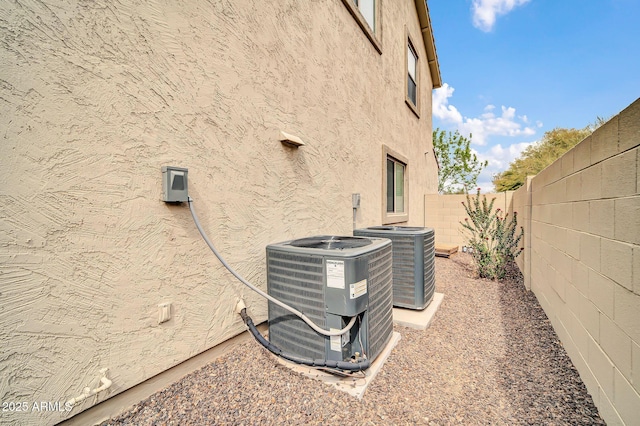 exterior details featuring central air condition unit, a fenced backyard, and stucco siding