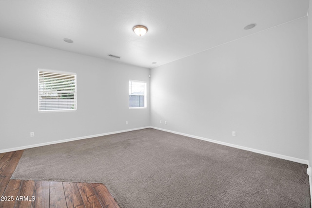 spare room featuring dark wood-style floors, visible vents, and baseboards