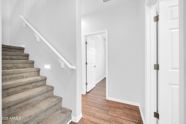 stairway featuring visible vents, baseboards, and hardwood / wood-style flooring