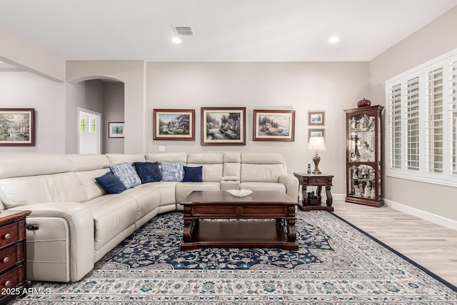 living room with visible vents, arched walkways, wood finished floors, baseboards, and recessed lighting